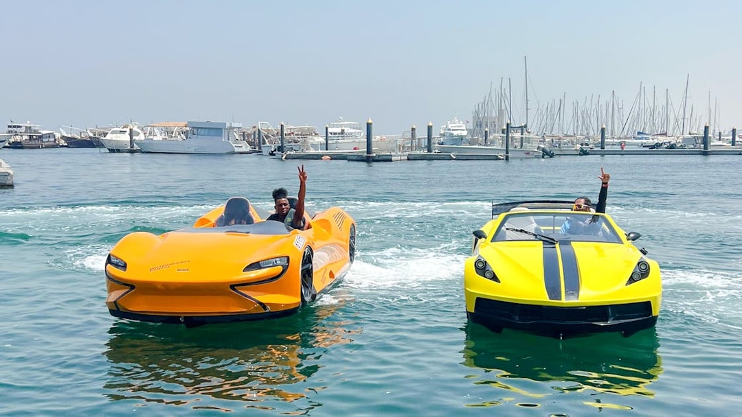 Two men driving jet cars on water in Dubai with marina skyline in background.