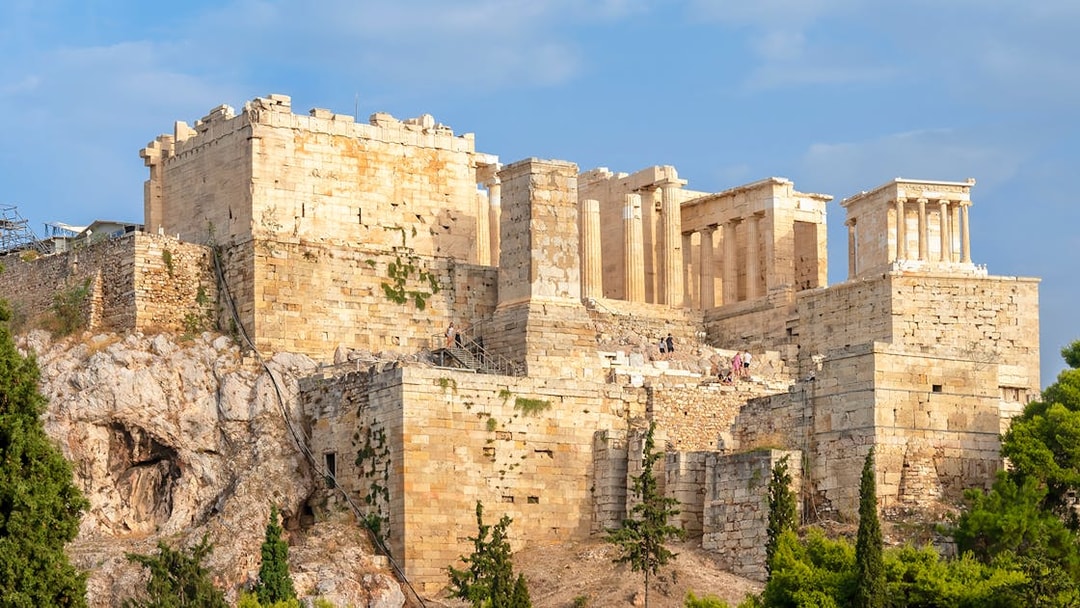 Acropolis in Athens with tourists on a guided tour, showcasing ancient ruins and architecture.
