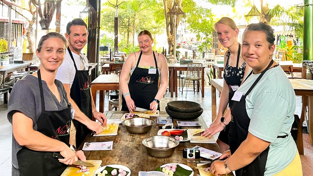 Participants chopping ingredients at Nia Balinese Cooking Class in an outdoor setting.