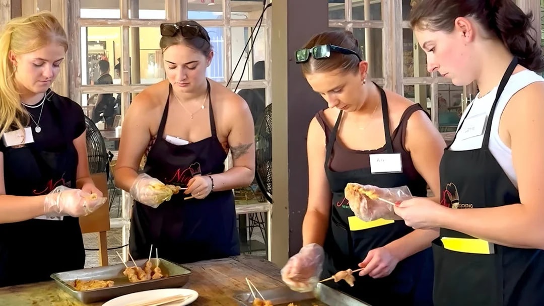 Participants preparing satay skewers at Nia Balinese Cooking Class.