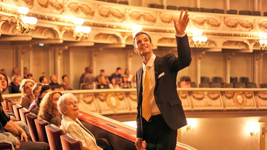 Tour guide leading a group through the ornate interior of the Semperoper in Dresden.