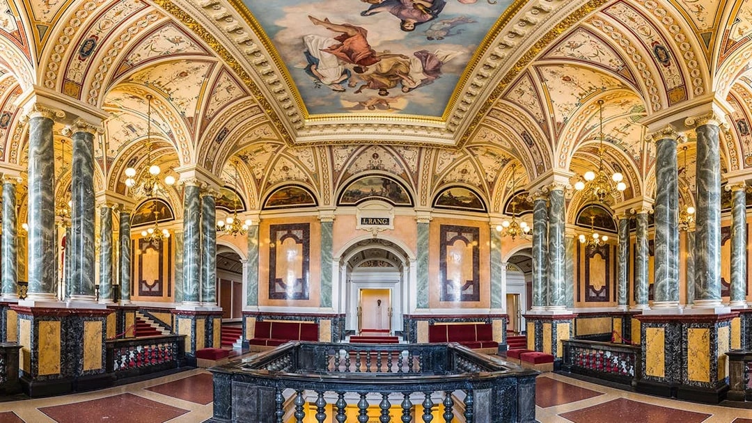 Ornate interior of the Semperoper in Dresden with marble columns and detailed ceiling frescoes.