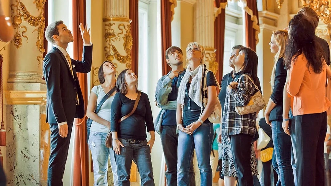 Tour group listening to a guide inside the ornate Semperoper, Dresden.