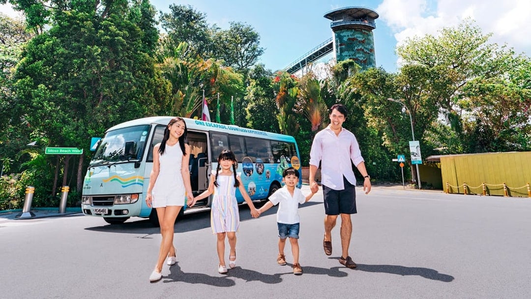 Family walking in front of a colorful tour bus on Sentosa Island.