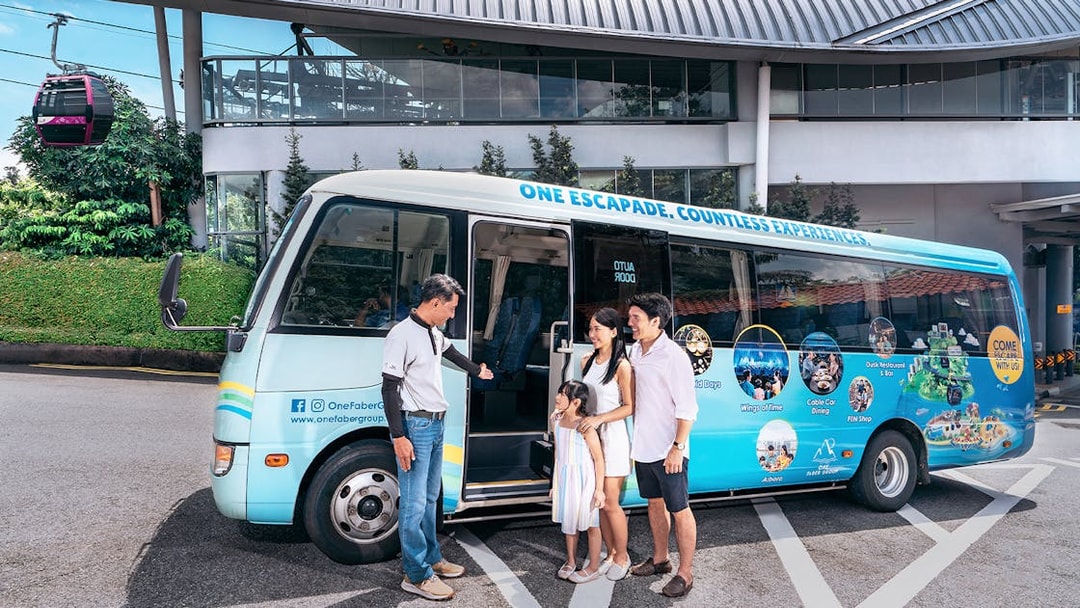 Family boarding a tour bus for Sentosa Island guided bus tour, with cable car station in background.