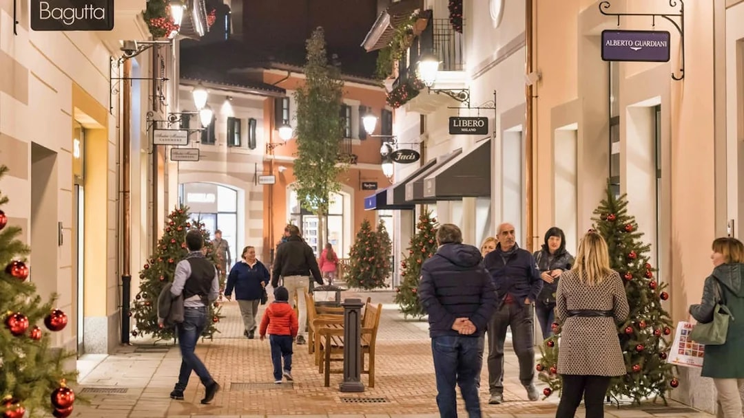 Shoppers walking through decorated street at Serravalle Designer Outlet near Milan.