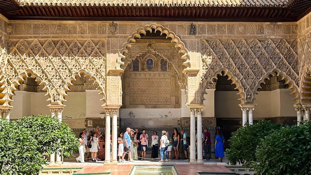 Visitors exploring the intricate arches of the Alcazar of Seville on a guided tour.