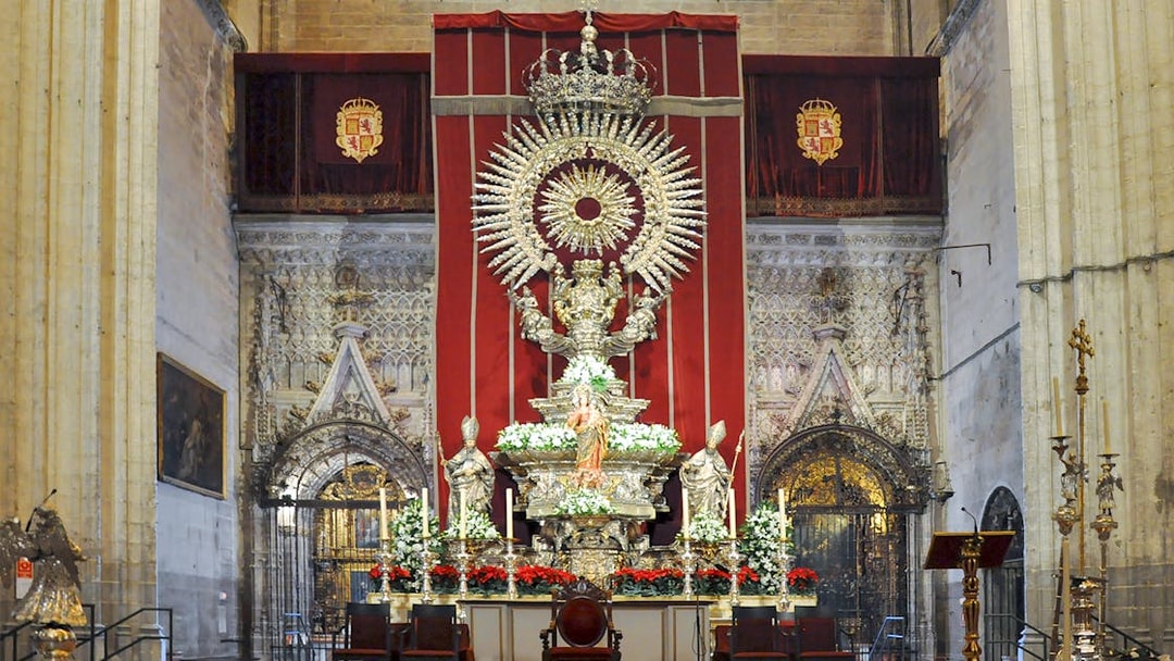 Altar of Seville Cathedral adorned with ornate sculptures and floral arrangements.