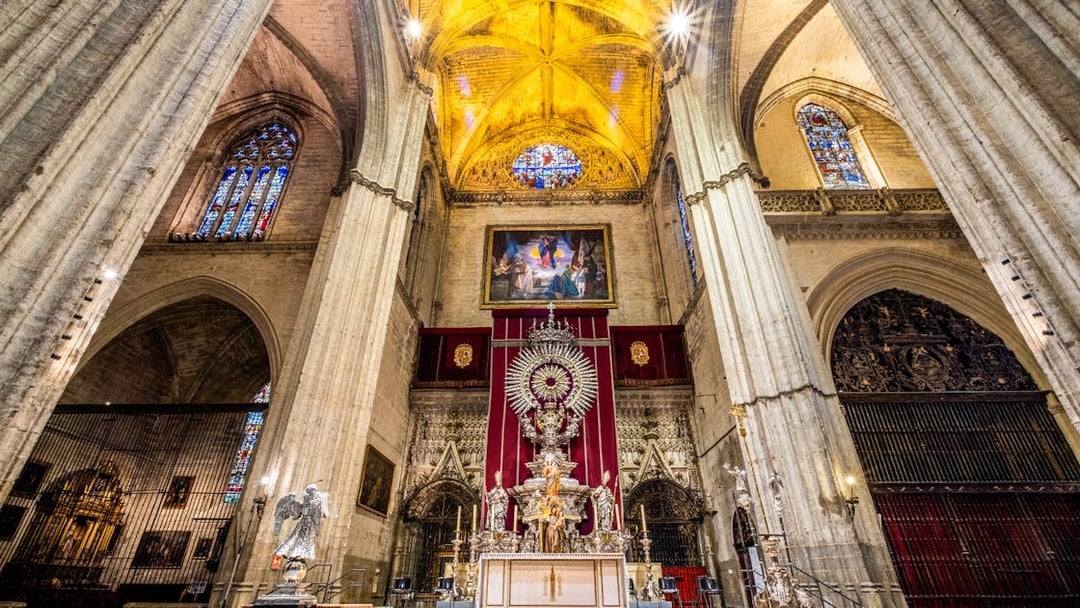 Interior of Seville Cathedral with ornate altar and stained glass windows, part of Exclusive Cathedral & Giralda Tour.