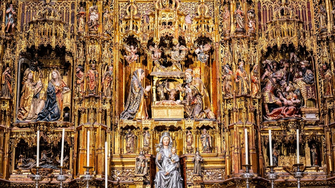 Intricate altarpiece in Seville Cathedral, featuring religious sculptures and gold detailing.