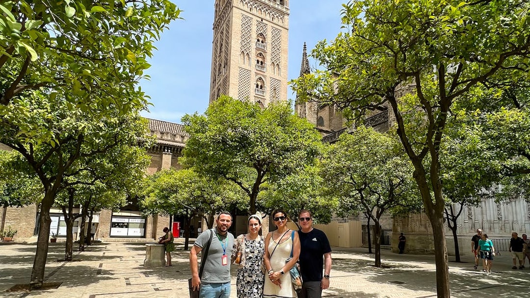 Visitors in courtyard with view of Giralda Tower, Seville, during guided tour.