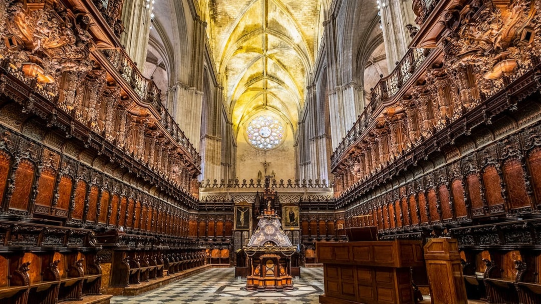 Cathedral interior with ornate wooden choir stalls and vaulted ceiling, Seville.