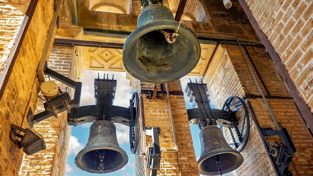 Bells of the Giralda tower in Seville, Spain against a blue sky.