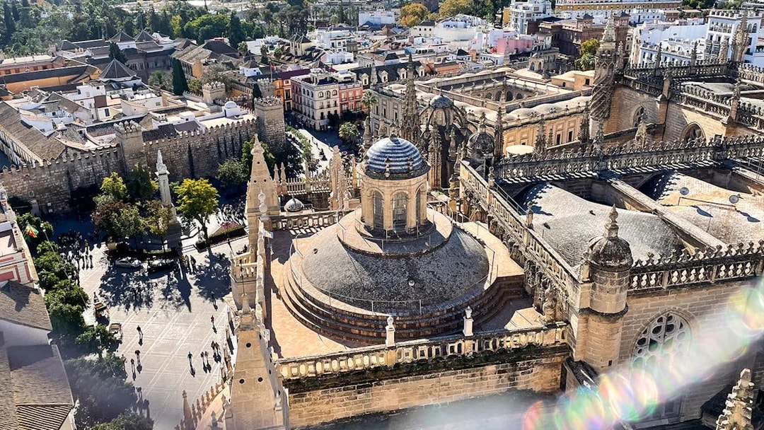 Aerial view of Seville Cathedral and Giralda tower with surrounding cityscape.