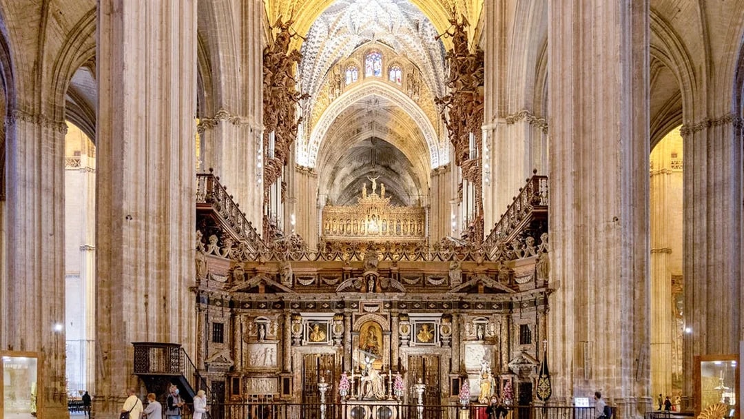 Seville Cathedral interior with ornate altar and vaulted ceilings.