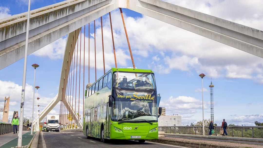 Seville hop-on hop-off bus crossing a bridge with modern architecture.