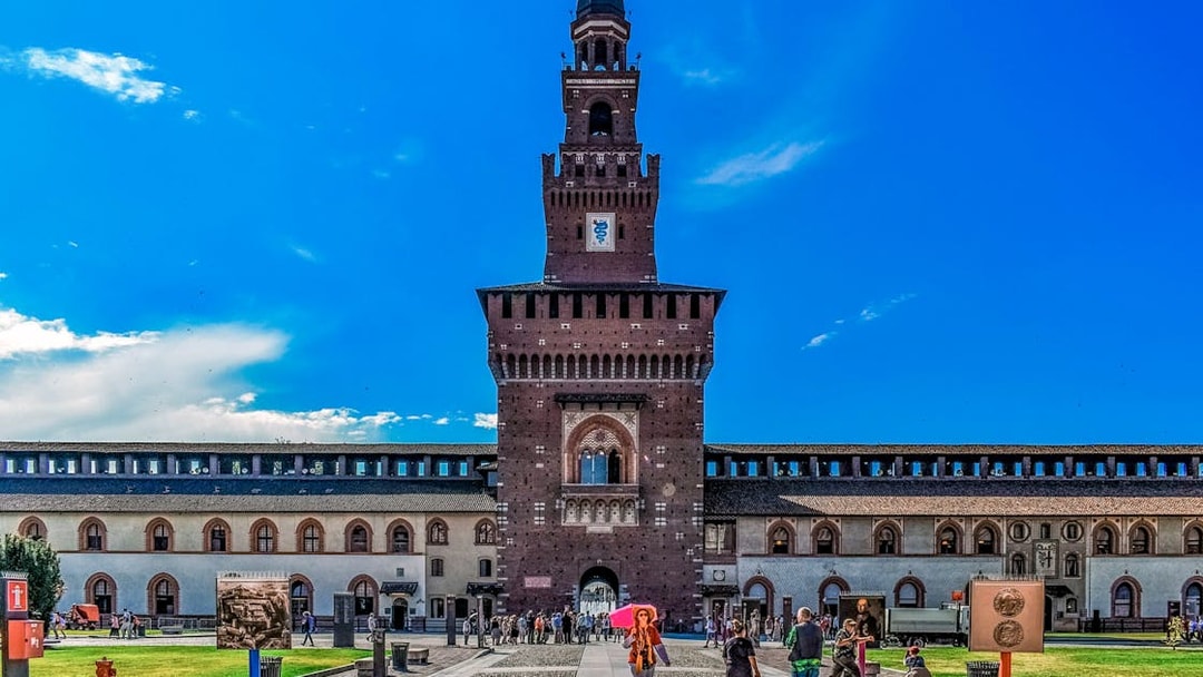 Sforza Castle entrance with visitors in Milan, Italy.