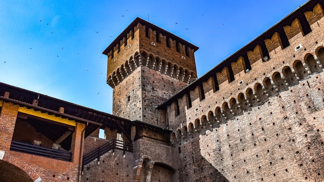 Sforza Castle brick tower and walls under a clear blue sky in Milan, Italy.