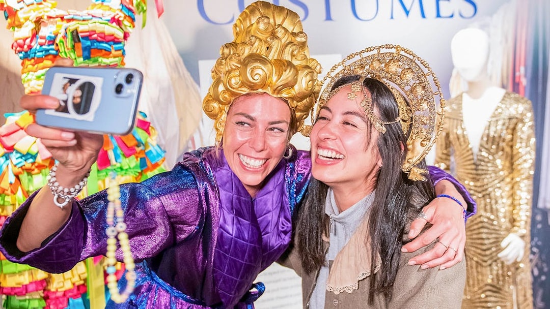 Visitors in colorful costumes taking a selfie at a museum exhibit during Globe Story and Guided Tours.