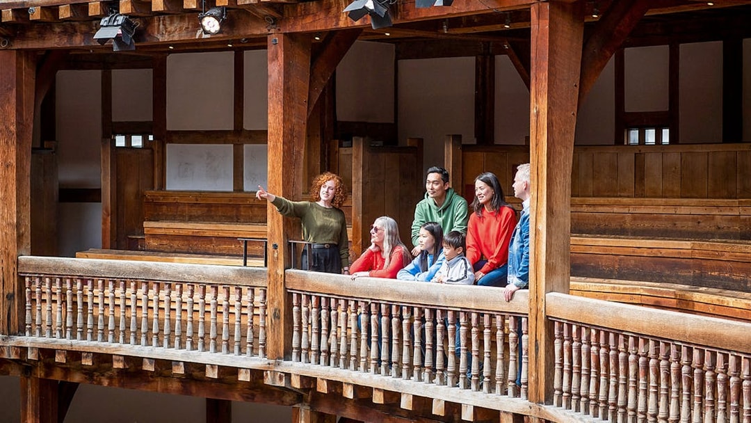 Tour guide explaining Shakespeare's Globe Theatre to visitors on a guided tour.