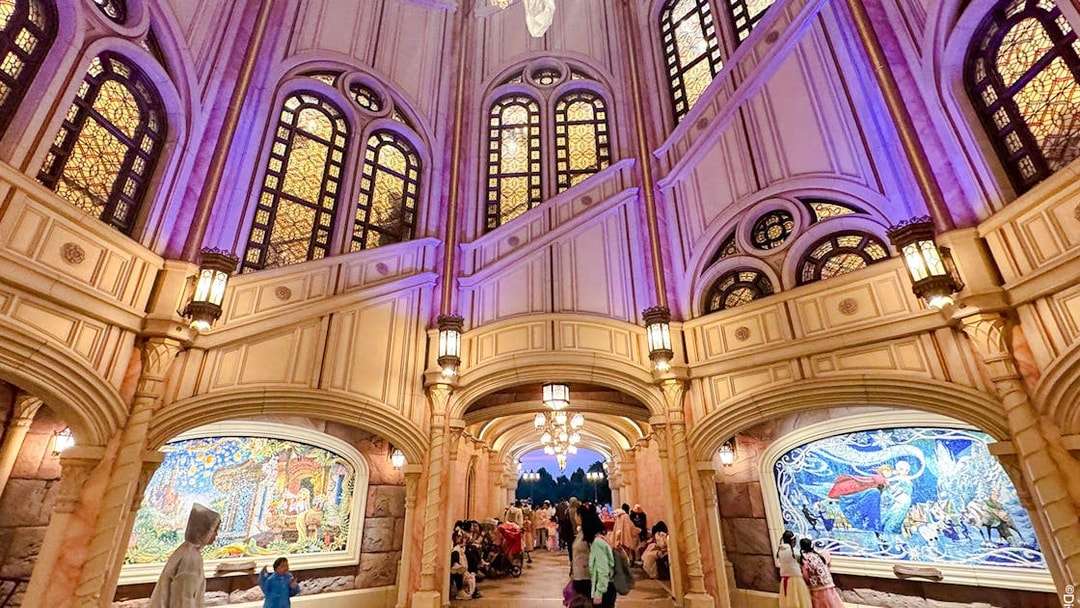 Interior of Shanghai Disney castle with stained glass windows and mosaic murals.