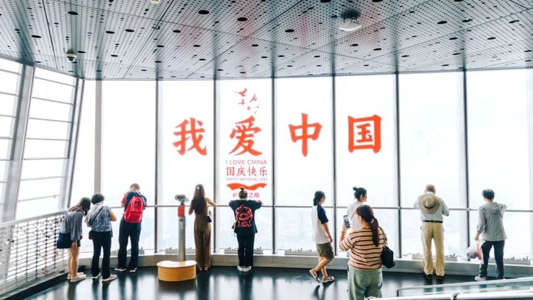 Visitors at Shanghai Tower observation deck with "I Love China" sign.