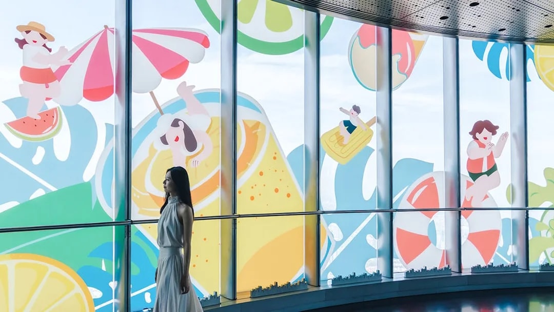 Woman walking past summer-themed cartoon decals on Shanghai Tower windows.