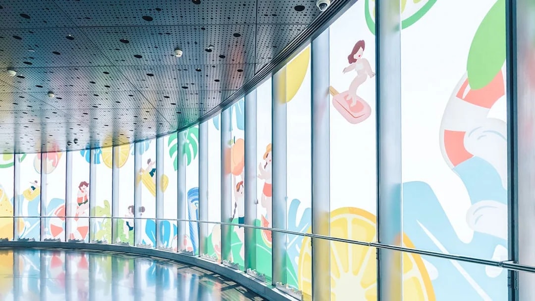 Curved hallway in Shanghai Tower with colorful window decorations.