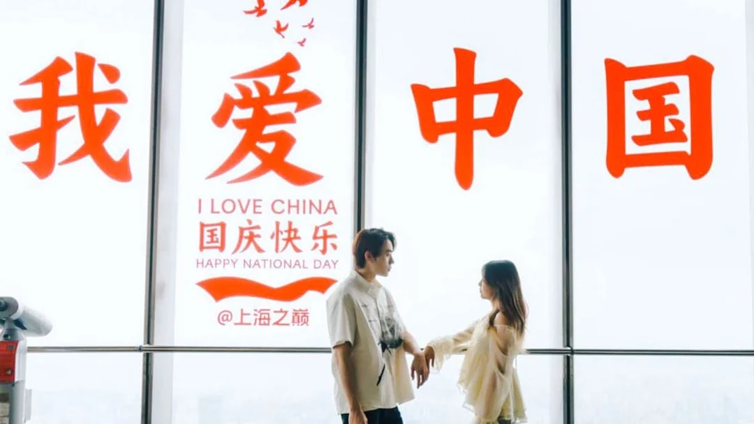 Couple standing inside Shanghai Tower with "I Love China" sign in background.