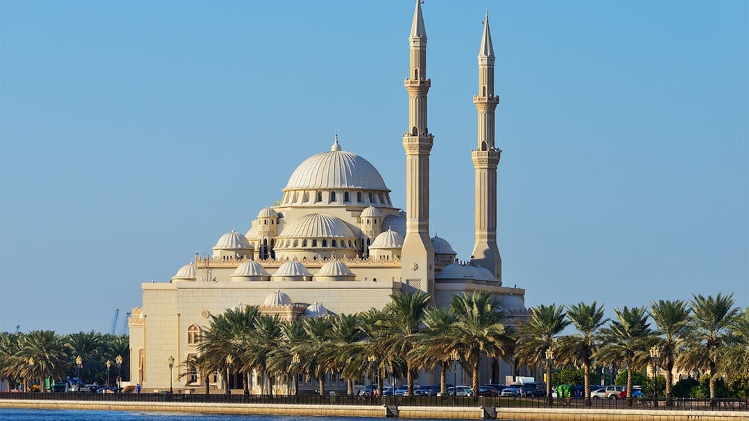 Sharjah Mosque with palm trees along the waterfront on the Hop-On-Hop-Off Bus Tour.