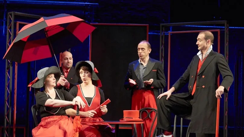 Performers in red and black costumes on stage during Showstopper! The Improvised Musical.