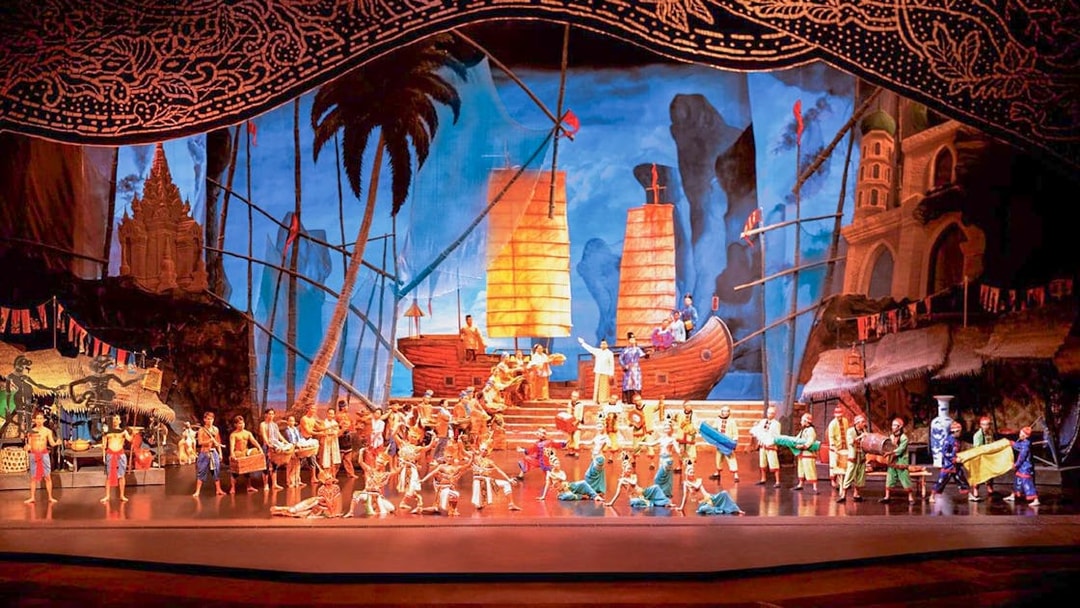 Performers on stage at Siam Niramit show in Phuket with traditional costumes and ship backdrop.