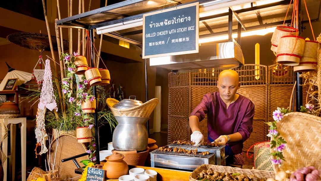 Vendor grilling chicken at buffet in Siam Niramit, Bangkok.