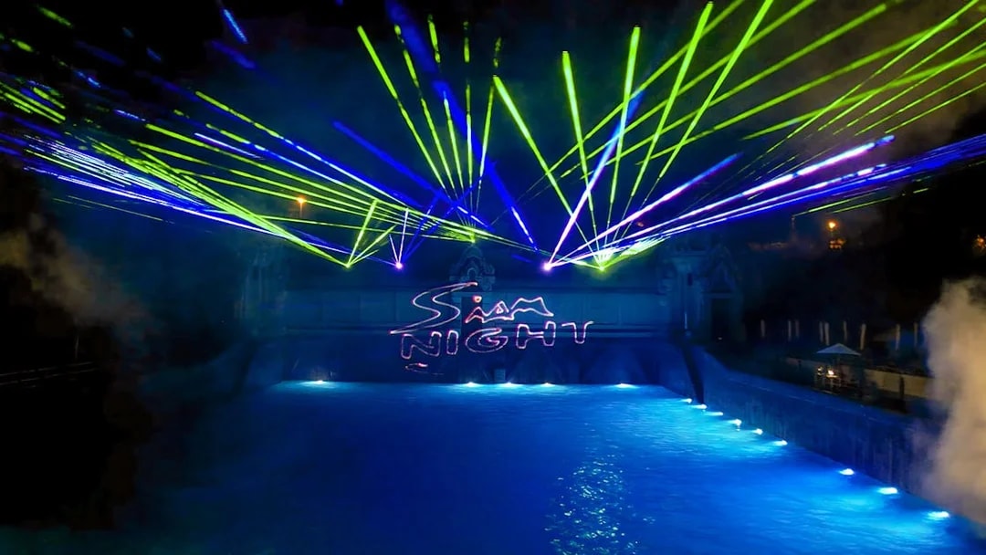 Laser show over water at Siam Park, illuminated at night.