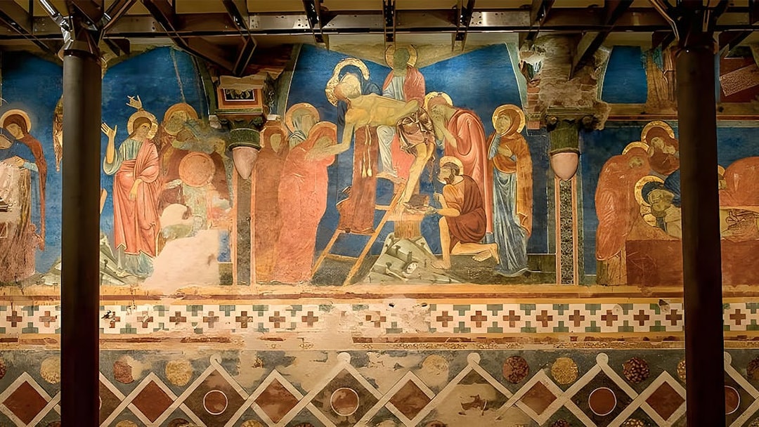 Tour group viewing frescoes in Siena Cathedral Crypt, Italy, with vibrant religious scenes.