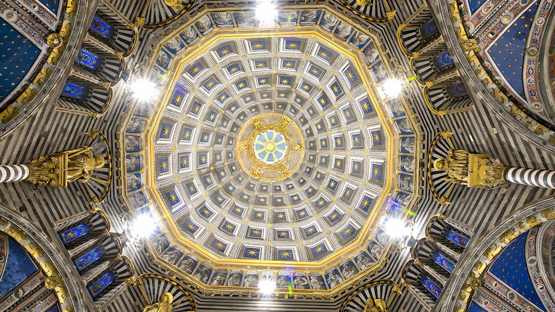 Siena Duomo dome interior with intricate gold and blue star patterns.