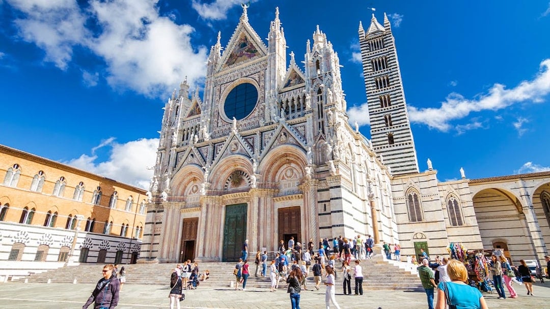 Siena Cathedral facade with visitors in Piazza del Duomo, Italy.