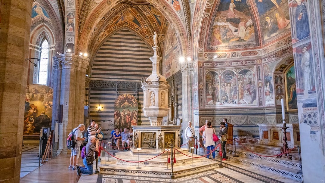 Tourists inside Siena Cathedral admiring frescoes and architecture, Italy.