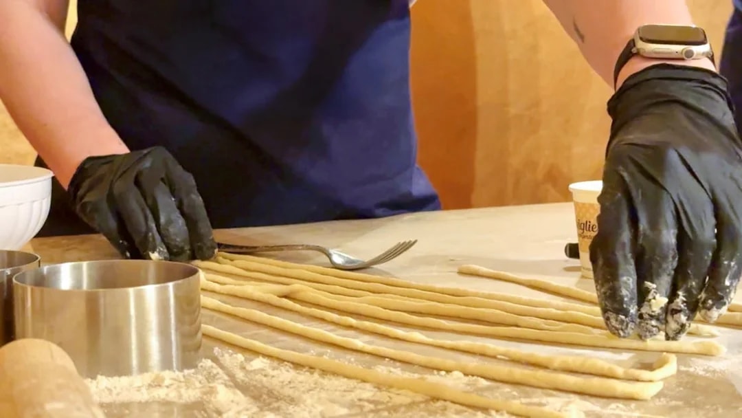 Participant preparing pasta during cooking class in Siena.