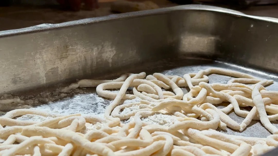 Fresh pasta dough on a floured surface during a cooking class in Siena.