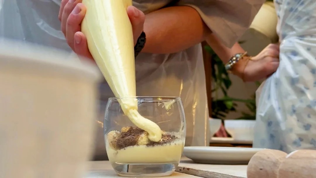 Tiramisu being prepared in a glass during a cooking class in Siena.