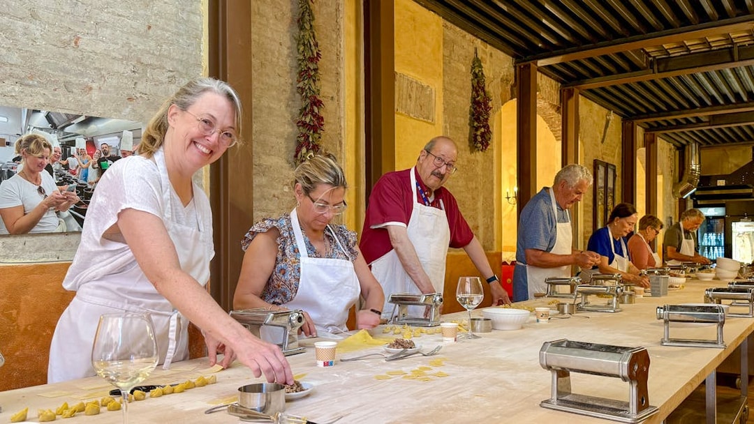 People in Siena cooking class making pasta at a long table with pasta machines.