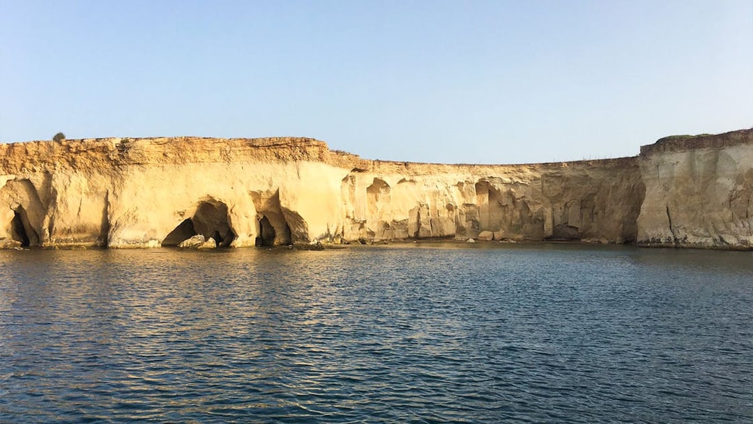 Sea caves along the rocky coastline of Ortigia Island during a sightseeing cruise.
