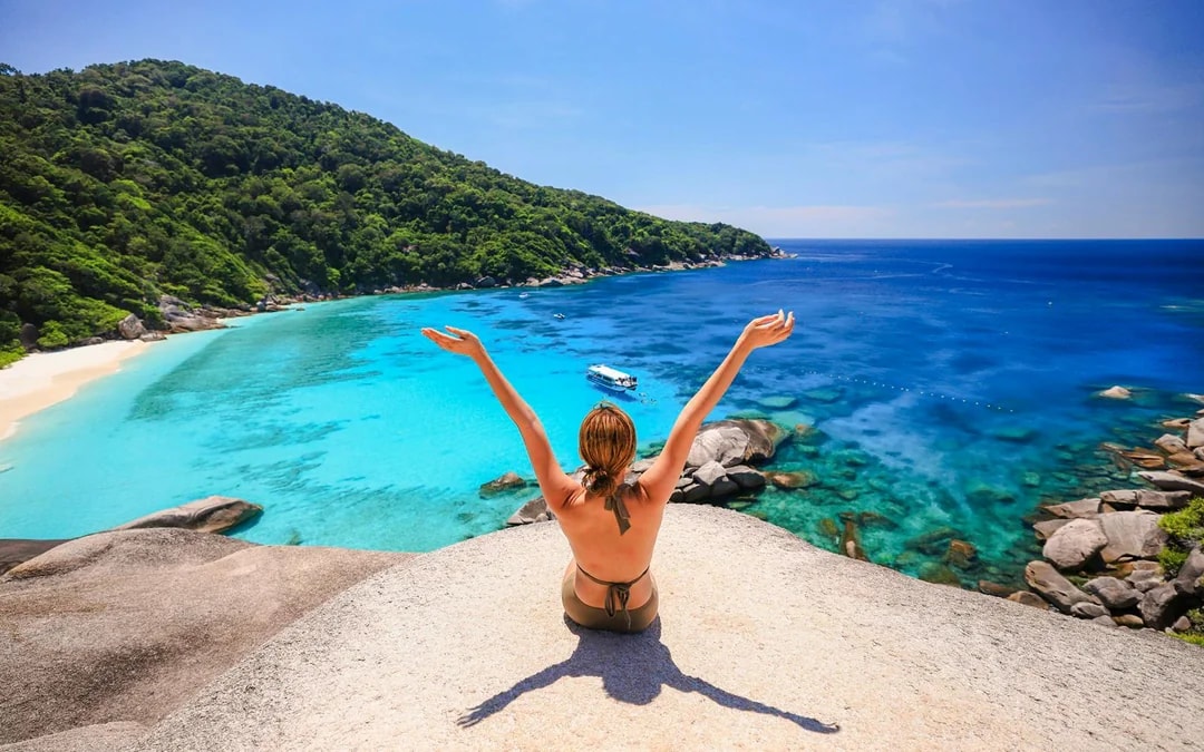 Person sitting on rock overlooking turquoise waters of Island No. 8, Similan Islands.