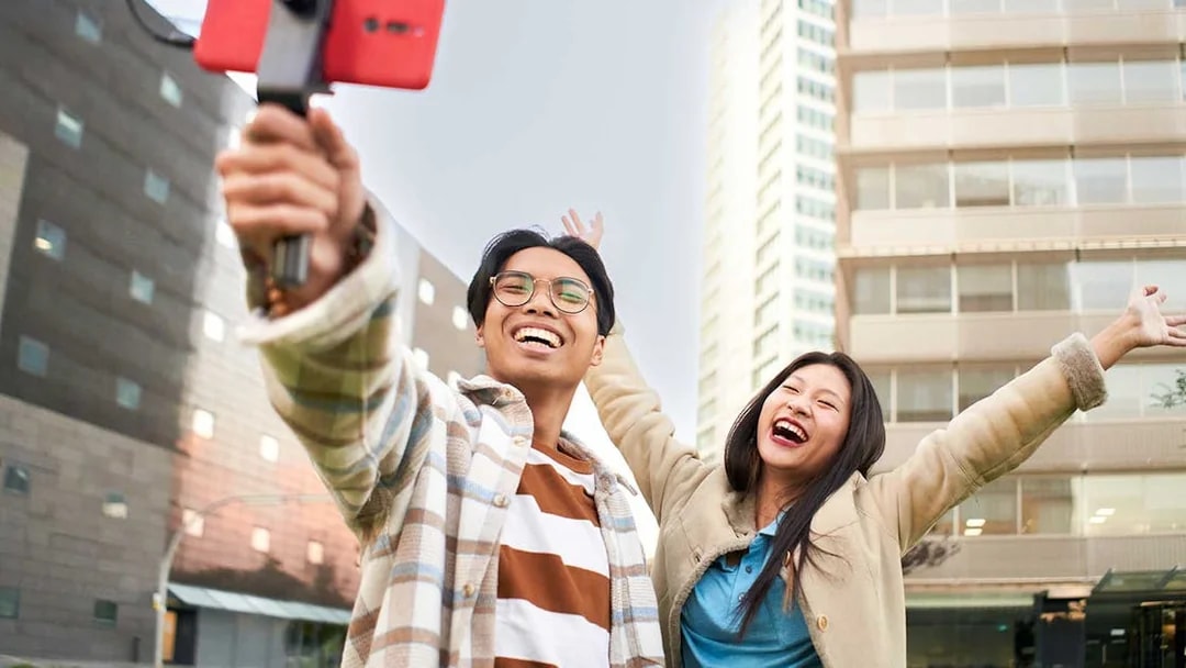 Couple taking a selfie in Singapore with city buildings in the background.