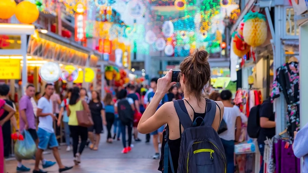 Tourist photographing vibrant street market in Singapore.