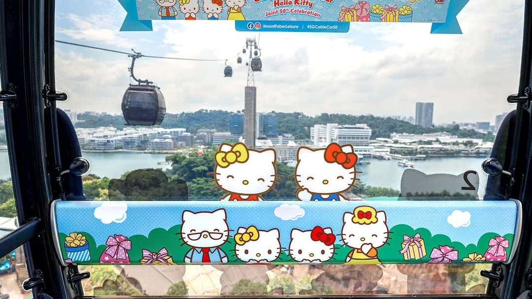 Singapore Cable Car decorated with Hello Kitty theme, overlooking cityscape and harbor.