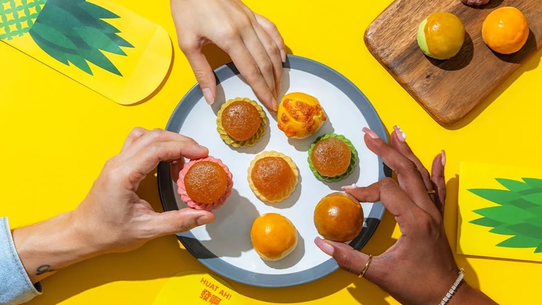 Hands reaching for traditional pastries on a plate, Singapore Cable Car Sky Pass.