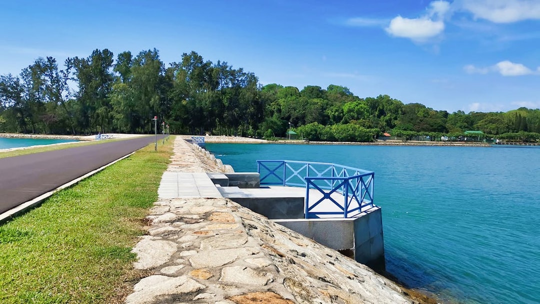 Pathway along the waterfront on Kusu Island, Singapore, with lush greenery in the background.