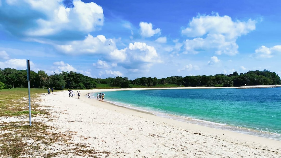 Visitors walking along the sandy beach on St John's Island, Singapore.